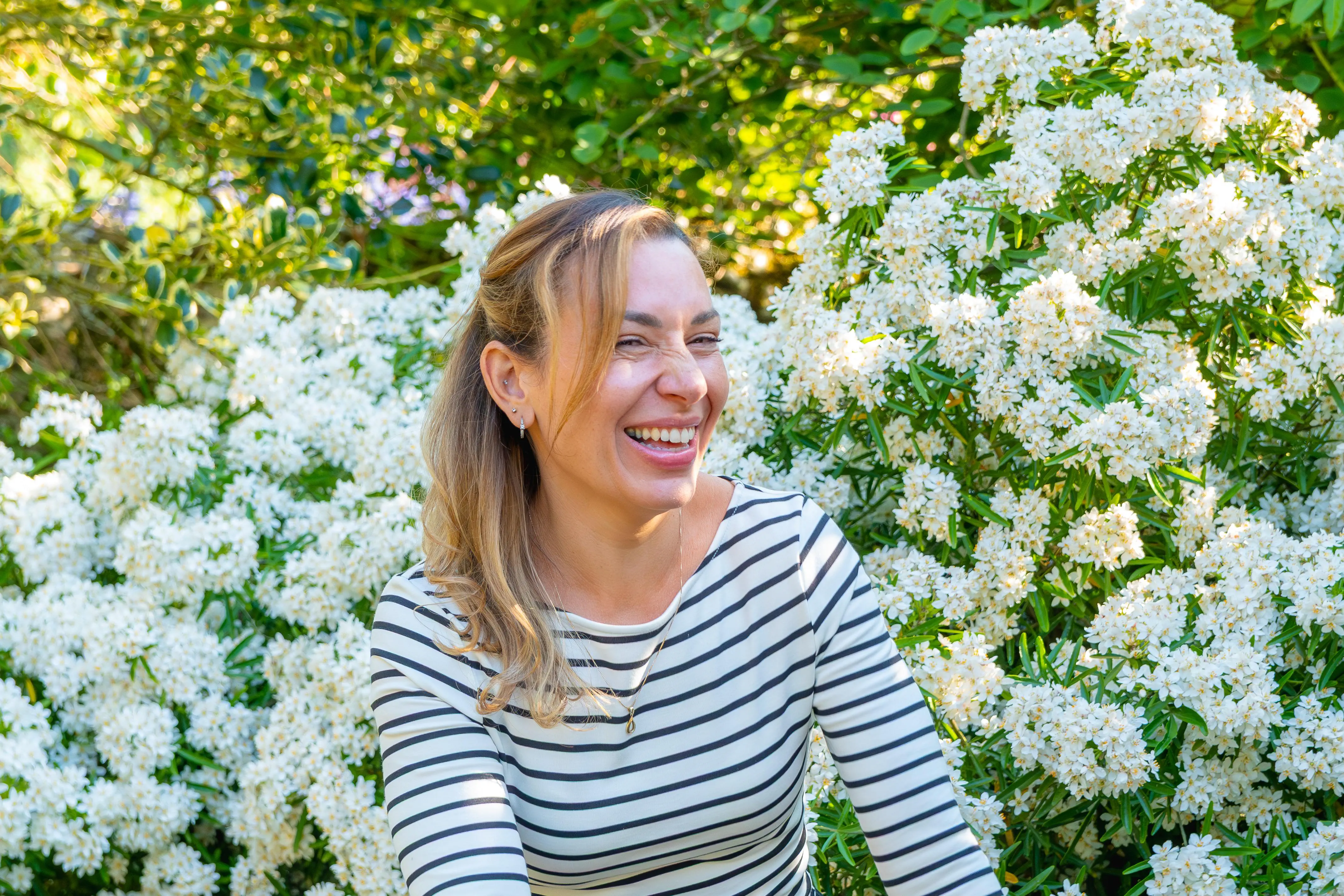 A female coach smiles in a beautiful flowery garden